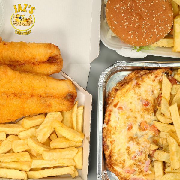 An open cardboard box from Jaz's Takeaway containing a mixed platter of red-battered fish, fried onion rings, and golden chips with a lemon wedge